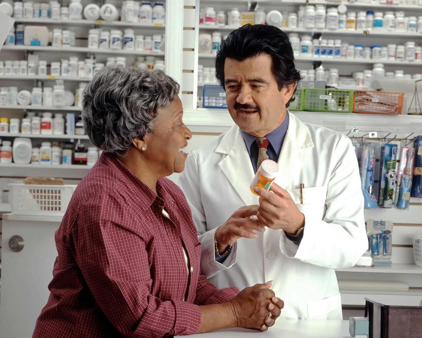 A pharmacist showing a medicine bottle to a customer